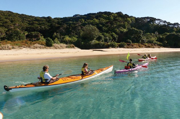 Quietly gliding on perfectly still waters kayakers enjoy the Bay of Islands.