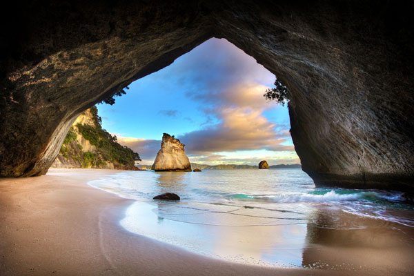 Water flowing lightly through a cove on the beach, behind the cove a magnificent rock is rising out of the shallow waters.