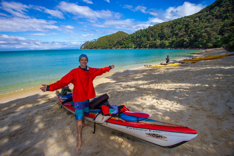 A kayaker having finished paddling for the day rests on the shores of Abel Tasman.