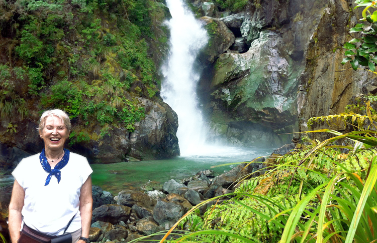 Hiker enjoying one of the many waterfalls - Hollyford Track