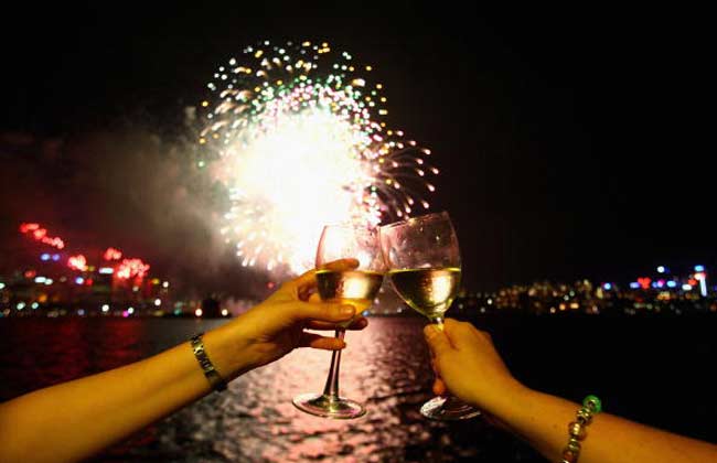 Two people enjoying fireworks with glasses of wine.