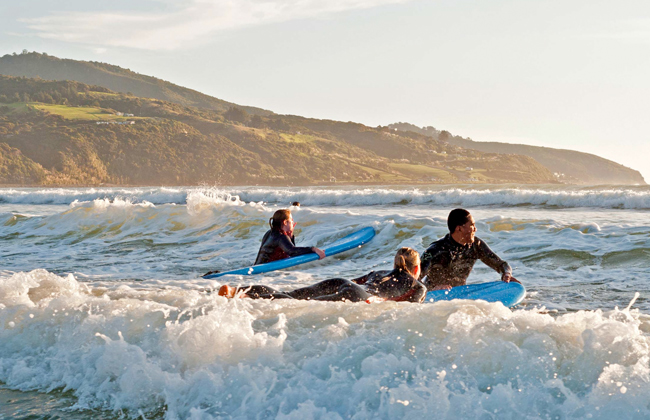 Three people catching a wave during a surf lesson.
