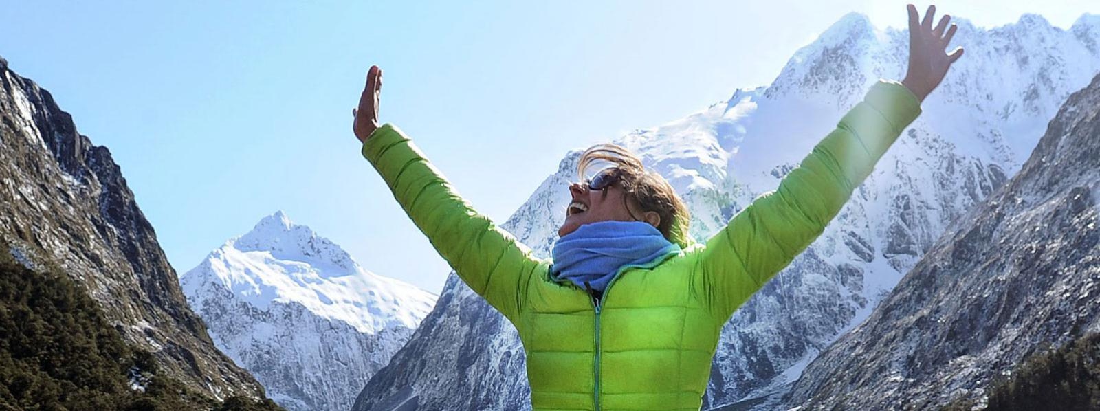 Arms in the air, rejoicing at the natural beauty among New Zealand's snow capped mountains. 