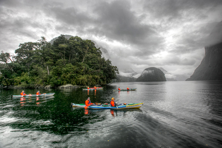 Group of people kayaking in moody rainy Doubtful Sound