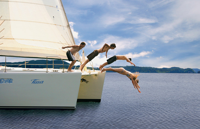 Funny picture of kids jumping into the water from a catamaran.