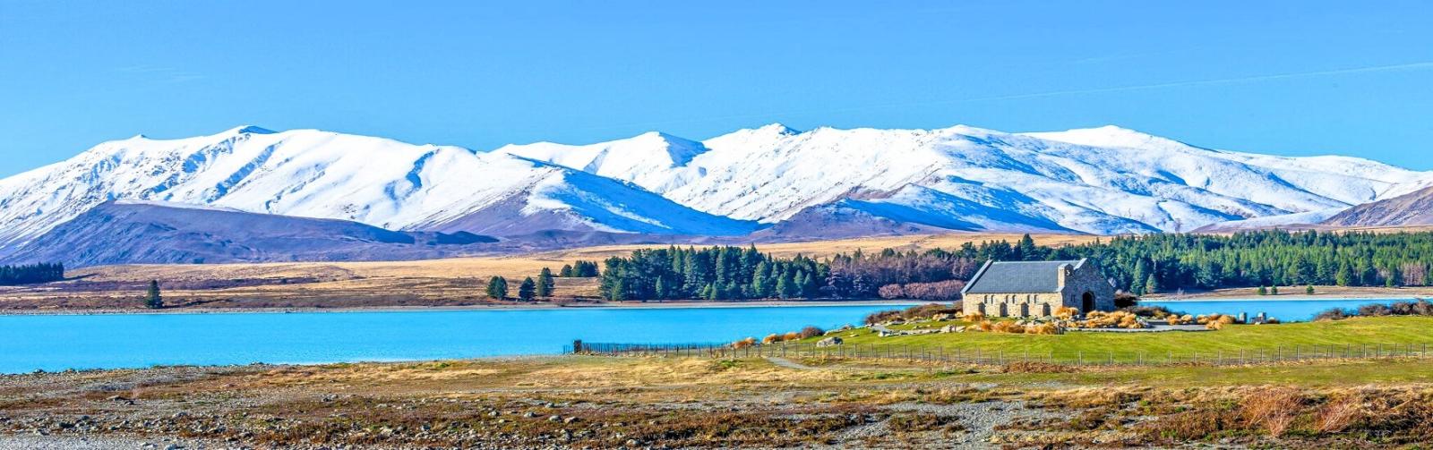 Lake Tekapo with Church of the Good Shephard and snow capped mountains