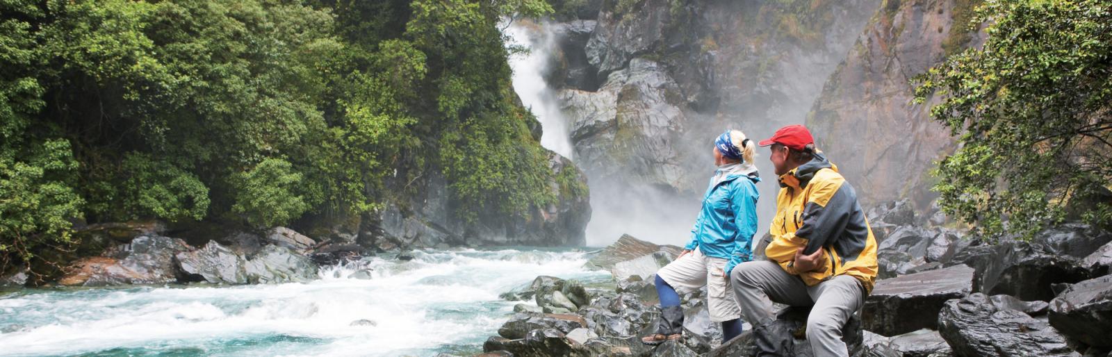 Hikers observe powerful waterfalls on the Hollyford Track.
