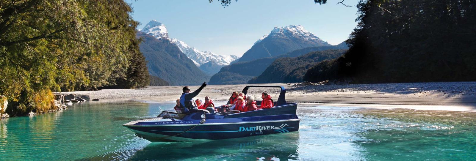 Jet boat stopped in the Dart River with passengers enjoying the scenery.