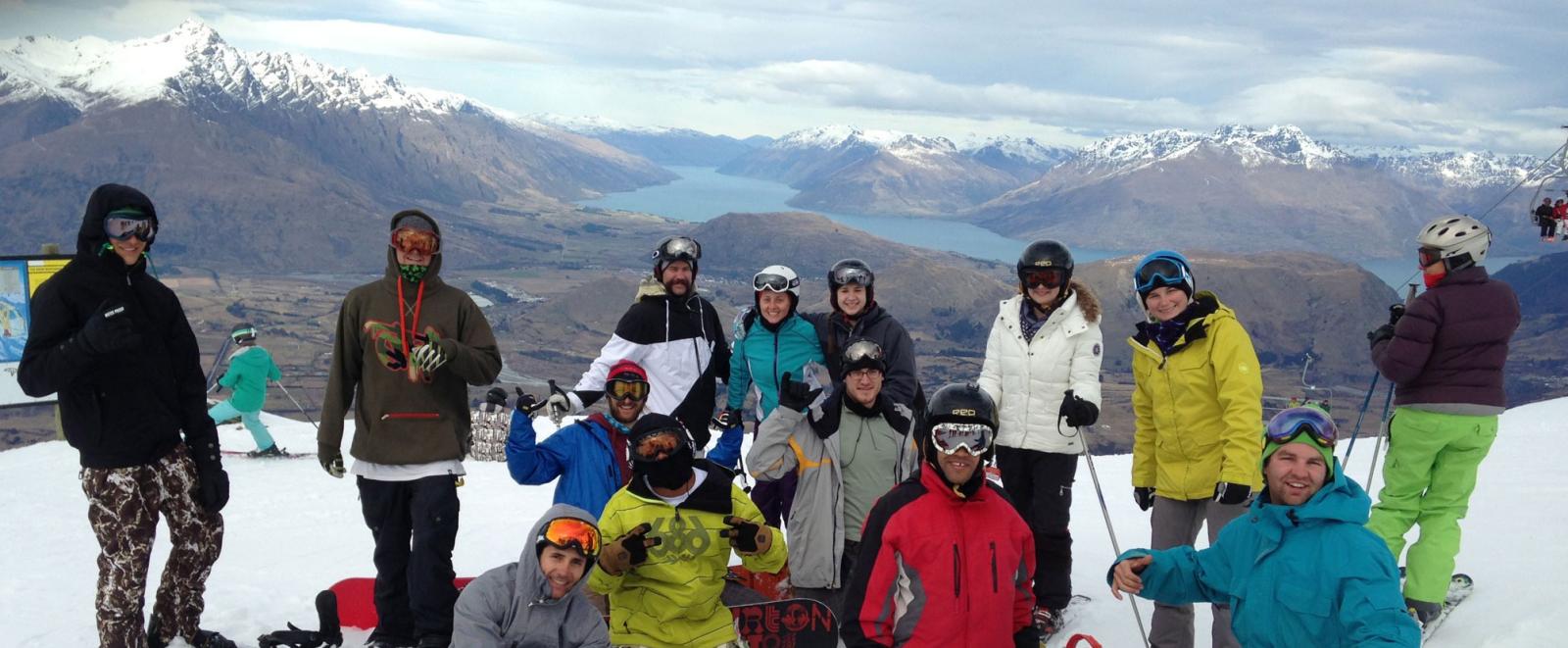 A very happy ski group sitting atop a Queenstown skifield.