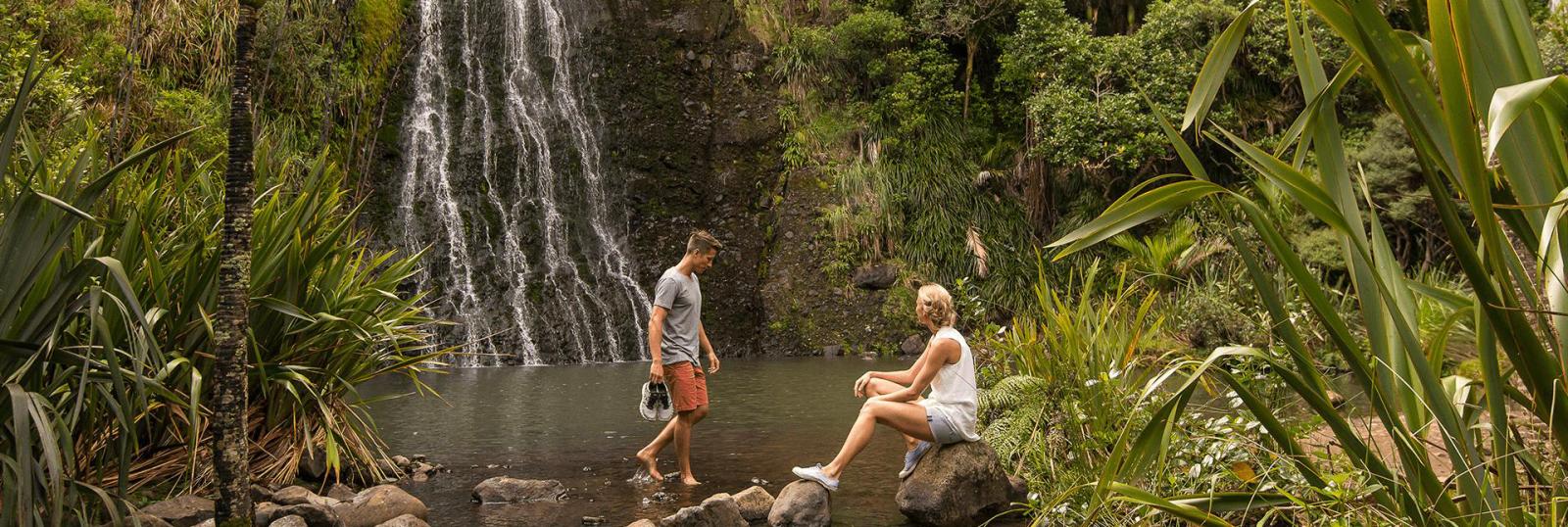 Couple enjoying resting by a beautiful waterfall during their South Island hike.