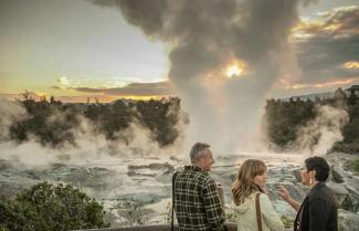couple standing next to a geyser in Rotorua
