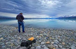 Man taking photo of beautiful Lake Tekapo New Zealand